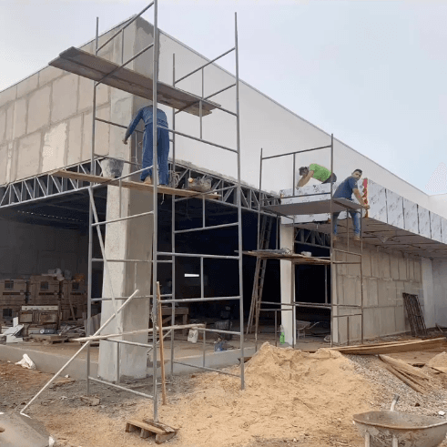 Obra comercial con andamios y operarios trabajando bloque BLOCOBR